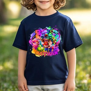 Puede incluir: Una camiseta azul marino de manga corta con un estampado gr&aacute;fico colorido de varios personajes de videojuegos, incluidos Mario, Luigi, Yoshi y Bowser. El dise&ntilde;o incluye un n&uacute;mero ocho grande y el nombre NATHAN en letras amarillas.