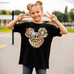 Puede incluir: Camiseta negra con un dise&ntilde;o colorido de la cabeza de Mickey Mouse compuesto por varios personajes de Disney. El dise&ntilde;o incluye a Mickey, Minnie, Donald y Goofy. La camiseta est&aacute; hecha de un material suave.
