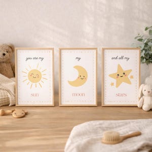 May include: Three framed art prints with a celestial theme. Each print features a smiling sun, moon, and star with the phrases "you are my sun", "my moon", and "and all my stars". The prints are in light wood frames.