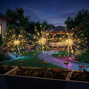 Puede incluir: Tres luces solares de jardín con diseño de estrella iluminan un jardín al anochecer. Cada luz tiene un grupo de pequeños LED blancos cálidos que irradian hacia afuera. Las luces están colocadas en un parterre con un cenador al fondo.