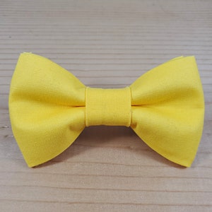 May include: A bright yellow bow tie made of fabric.