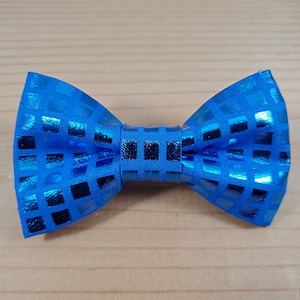 May include: A blue bow tie with a checkered pattern. The bow tie is made of a shiny fabric.