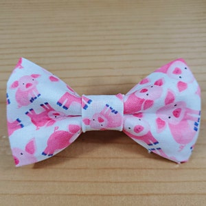 May include: A white bow tie with a pink and blue pig pattern.
