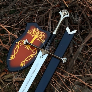 May include: A metal sword with a silver blade featuring engraved star symbols and runic text, a metallic crossguard, and a black handle. It is accompanied by a black scabbard and a shield-shaped wall plaque displaying a gold tree illustration.