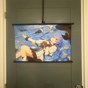 May include: A horizontal wall scroll featuring an anime-style illustration of a character with long purple hair, wearing a white and dark blue outfit, lying on a blue water-like surface while holding a brown book, with a staff and papers nearby.