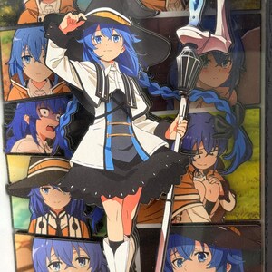 May include: A multi-layered acrylic art piece featuring a central anime character with long blue hair, wearing a black witch hat, white jacket, and black skirt, holding a staff. The background consists of a collage of various character expressions.
