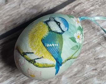 Blaumeise und Blüten Ostern Ornament. Miniaturmalerei eines Vogels auf der Schale eines echten Eis.