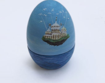 Painted wooden egg. Hollow egg with a painting of Brighton Pavilion flying over the sea, carried by seagulls. Perfect to hide a ring inside!