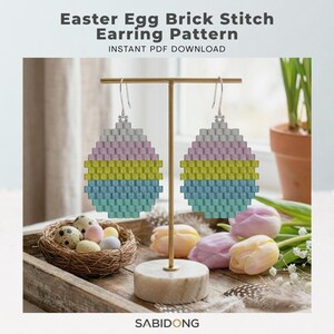 May include: Easter Egg Brick Stitch Earring Pattern INSTANT PDF DOWNLOAD. A pair of beaded earrings shaped like eggs with horizontal stripes in light gray, soft pink, lime green, and light blue, hanging from silver-toned metal hooks.