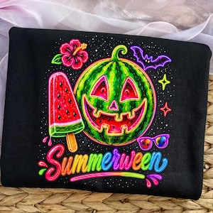 May include: A black t-shirt featuring a vibrant neon graphic of a watermelon carved like a jack-o'-lantern, a watermelon popsicle, a hibiscus flower, a bat, and sunglasses. The word Summerween is printed in a colorful script font at the bottom.