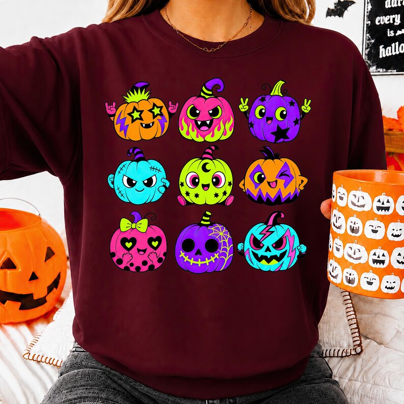 Puede incluir: Una sudadera de cuello redondo color granate con un estampado gr&aacute;fico de nueve calabazas estilizadas en varios colores, incluyendo naranja, rosa, morado, azul y verde lima. Las calabazas muestran diversas expresiones faciales y patrones.