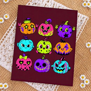 Puede incluir: Una impresi&oacute;n rectangular de color granate oscuro con nueve calabazas de dibujos animados coloridas con diversas expresiones y patrones, incluyendo ojos en forma de estrella, rayos, telara&ntilde;as y lunares en tonos ne&oacute;n vibrantes.