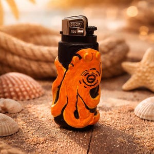 Peut inclure: Un briquet noir avec un motif de poulpe orange. Le briquet a un dessus en métal argenté avec le texte "PROF G24". Il est posé sur une surface en bois avec du sable, des coquillages et une corde.