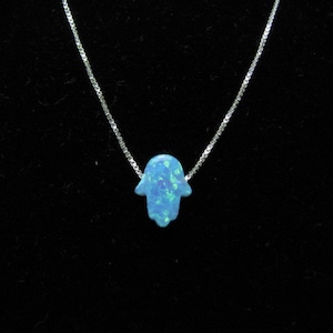May include: A silver chain necklace with a blue opal hamsa hand charm.