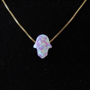 Op de afbeelding: Een gouden ketting met een hanger in de vorm van een Hamsa-hand van paarse opaal.