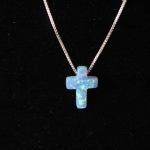 May include: A silver chain necklace with a blue opal cross pendant.
