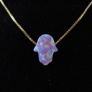 Op de afbeelding: Een gouden ketting met een hanger in de vorm van een hamsa-hand van paarse opaal.