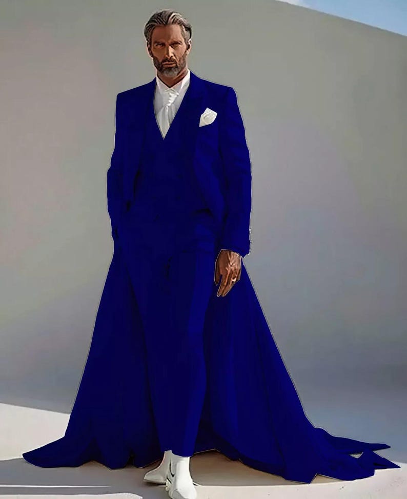Puede incluir: Un llamativo traje azul cobalto con una cola extendida. El traje presenta una chaqueta a medida con un pa&ntilde;uelo blanco y un pantal&oacute;n a juego. El modelo lleva una camisa blanca y botas blancas. El traje es una audaz declaraci&oacute;n de moda.
