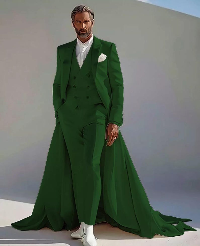 Puede incluir: Un traje de tres piezas verde esmeralda con una larga cola. El traje incluye una americana, un chaleco y un pantal&oacute;n. El modelo lleva una camisa blanca y botas blancas. Un pa&ntilde;uelo blanco est&aacute; en el bolsillo de la americana.