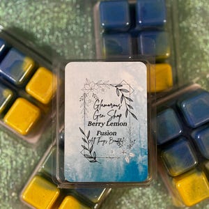 May include: Wax melt cubes in clear plastic packaging. The cubes are yellow and blue. The label reads "Glamorous Gen Shop Berry Lemon Fusion All Things Beautiful."