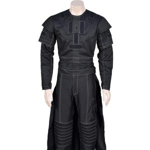 Puede incluir: Traje negro con costuras blancas, que consta de una parte superior de manga larga y pantalones. La parte superior tiene cuello redondo y detalles en los hombros. Los pantalones tienen rodilleras y un bolsillo de carga. El conjunto se muestra en un maniquí.