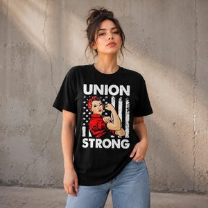 Könnte beinhalten: Ein schwarzes Kurzarm-T-Shirt mit einem Grafikdruck einer Person in rotem Hemd und rotem gepunktetem Kopftuch, die den Arm beugt. Das Design enthält eine stilisierte amerikanische Flagge und den weißen Text UNION STRONG.