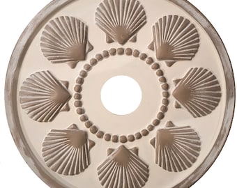May include: A white ceiling medallion with a distressed finish features eight brown seashell designs around a central circle. The seashells have a raised, textured surface.