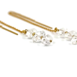 May include: A pair of gold chain earrings with clear quartz crystals dangling from the ends.
