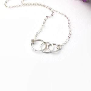 May include: A silver necklace with three interlocking circles pendant.