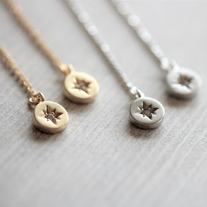 Puede incluir: Tres delicados collares con un colgante de estrella. Los collares están hechos de cadenas de oro, plata y oro rosa. Cada colgante presenta una pequeña estrella con una piedra transparente en el centro.