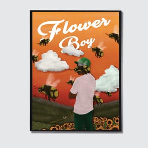 Könnte beinhalten: Kunstdruck mit dem Schriftzug "Flower Boy" in weiß auf orangefarbenem Hintergrund. Das Kunstwerk zeigt eine Person in einem rosa Hemd und grüner Hose, umgeben von Bienen und Wolken. Am unteren Rand des Bildes sind Sonnenblumen zu sehen.