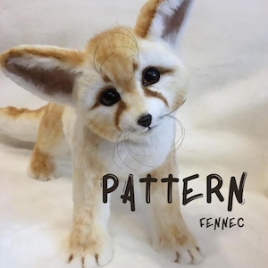May include: A Fennec fox soft toy, cream and tan in colour, with large ears and a fluffy tail. The toy has dark eyes and the words "PATTERN" and "FENNEC" in black text.