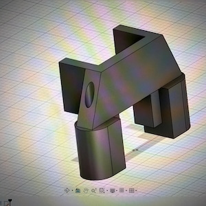 Könnte beinhalten: Ein 3D-gerendertes, dunkelgraues mechanisches Bauteil mit L-förmigem Design. Es hat eine zylindrische Basis, rechteckige Abschnitte und eine ovale Öffnung. Das Objekt befindet sich vor einem Rasterhintergrund.