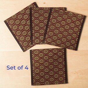 Pode incluir: Conjunto de quatro bases decorativas. Cada base apresenta um padrão repetido de formas florais douradas dentro de uma grade hexagonal sobre um fundo bordô. As bordas são finalizadas com acabamento preto. O texto "Set of 4" é visível.