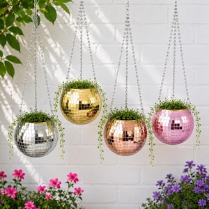 Peut inclure: Quatre jardinières suspendues sphériques recouvertes de carreaux de miroir carrés réfléchissants en argent, or, or rose et rose. Chaque jardinière est suspendue par une chaîne en métal argenté et contient une petite plante verte.
