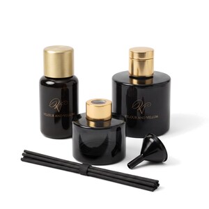 Puede incluir: Tres frascos difusores de vidrio negro con tapas de metal dorado, cada uno con el texto impreso en oro Velour and Vellum. El conjunto incluye un pequeño embudo de plástico negro y un paquete de varillas difusoras negras con una banda.