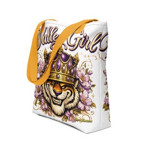 Op de afbeelding: Witte tote bag met een tijger met een juwelen kroon, omringd door paarse bloemen. De tas heeft mosterdgele bandjes en de woorden "Valley Girl" in een cursief lettertype. De tijgerafbeelding is gedetailleerd met gouden accenten.