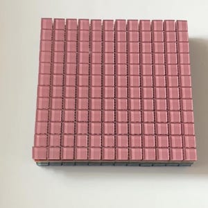 May include: A square sheet of small, dusty rose pink glass mosaic tiles arranged in a grid pattern. The individual tiles are square with slightly beveled edges, creating a uniform texture across the surface of the entire mosaic tile sheet.