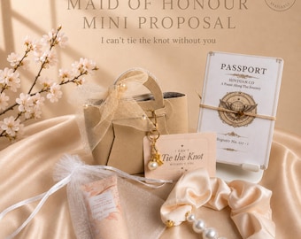 May include: A mini proposal gift set with a beige handbag, a passport-themed card, a scrunchie with pearls, and a hand cream tube. The set includes a card that says "I can't tie the knot without you."