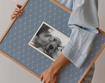Op de afbeelding: Een ingelijste, op maat gemaakte fotoprint met een zwart-wit afbeelding van een persoon die een hond kust. De lijst is van hout met een blauwe achtergrond met patroon en de tekst "Custom photo print".