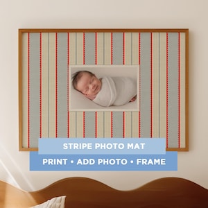 May include: A framed photo mat featuring a sleeping baby. The mat has a striped design in red, blue, and cream. The wooden frame surrounds the photo. Text on the mat reads: STRIPE PHOTO MAT, PRINT • ADD PHOTO • FRAME.
