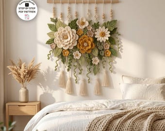 Puede incluir: Un tapiz de pared con flores y hojas de ganchillo en tonos crema, amarillo y verde, suspendido de una varilla de madera con borlas colgantes y cuentas de madera. El texto Care4youStudio STEP BY STEP PDF PATTREN es visible.