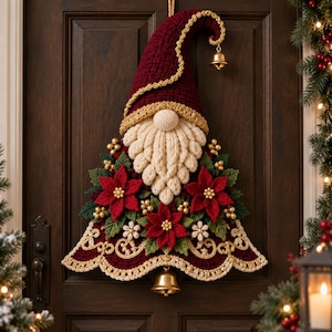 May include: A decorative crochet wall hanging shaped like a gnome with a tall, pointed burgundy hat, a cream-colored beard, and red poinsettia flowers. The piece features gold trim, small gold beads, and two gold bells hanging from the hat and base.
