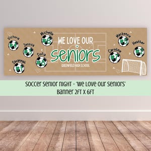 May include: A rectangular banner with a tan background featuring a white soccer field outline. It displays the text WE LOVE OUR seniors GREENFIELD HIGH SCHOOL, along with eight soccer ball graphics labeled with names and numbers 1 through 8.