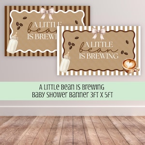 May include: A rectangular banner featuring a brown and white striped border, a scalloped frame, and a light brown center. The text reads A LITTLE BEAN IS BREWING. Graphics include a white baby bottle, coffee beans, a bow, and a coffee cup with latte art.