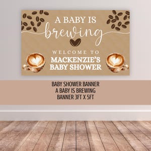 May include: A rectangular banner with a tan background featuring coffee bean illustrations, two cups of latte art, and the text A BABY IS BREWING WELCOME TO MACKENZIE'S BABY SHOWER. The banner includes text stating it is a 3ft x 5ft baby shower banner.