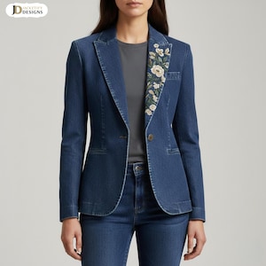 Puede incluir: Una blazer de mezclilla azul oscuro con bordado floral en la solapa. La blazer tiene un cierre de un solo botón y un corte entallado. El bordado floral presenta acentos blancos y verdes. La blazer se combina con unos vaqueros de mezclilla a juego.