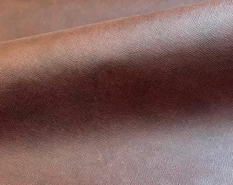 Könnte beinhalten: Nahaufnahme eines Stoffabschnitts mit strukturierter Oberfläche. Der Stoff hat einen Farbverlauf, der von einem hellen, fast rosa Farbton oben zu einem tieferen, rotbraunen Farbton unten übergeht. Das Material scheint glatt zu sein und möglicherweise Seide oder Satin.