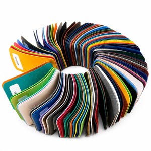 May include: A circular fan-shaped collection of numerous rectangular material swatches in a wide spectrum of colors including yellow, green, blue, red, and black. Each swatch features a rounded corner and a white label with printed text.