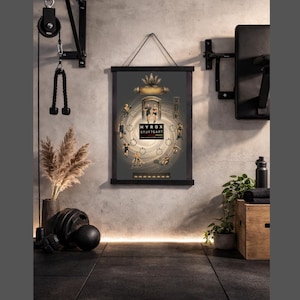 Peut inclure: Une affiche encadrée avec le texte "HYROX STUTTGART" est accrochée sur un mur de gymnase. L'affiche présente un design circulaire avec des personnages pratiquant diverses activités physiques. L'environnement de la salle de sport comprend des équipements d'exercice, une bouteille d'eau et une caisse en bois.